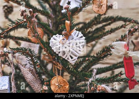 Arbre de Noël décoré d'une couronne en osier en forme de cœur et d'autres ornements de Noël faits main sans déchets Banque D'Images