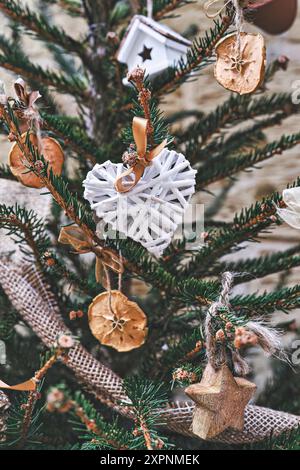 Arbre de Noël décoré d'une couronne en osier en forme de cœur et d'autres ornements de Noël faits main sans déchets Banque D'Images