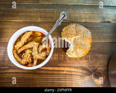 Délicieuse assiette de soupe de tripes de bœuf avec du pain frais sur le dessus de table en bois Banque D'Images