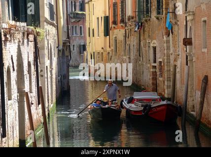 Un gondolier transporte les touristes dans une gondole sur les canaux de Venise en Italie. Venise est une ville du nord-est de l'Italie et la capitale du VE Banque D'Images