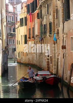Un gondolier transporte les touristes dans une gondole sur les canaux de Venise en Italie. Venise est une ville du nord-est de l'Italie et la capitale du VE Banque D'Images