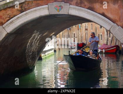 Un gondolier transporte les touristes dans une gondole sur les canaux de Venise en Italie. Venise est une ville du nord-est de l'Italie et la capitale du VE Banque D'Images