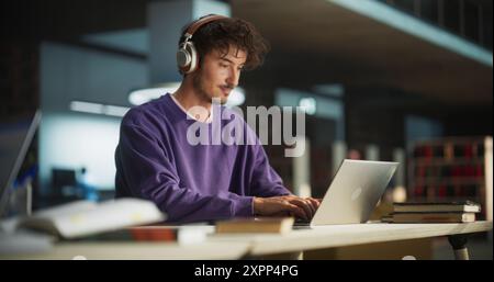 Personne écrivant dans le carnet de notes. Focus passer à un étudiant réfléchi à l'aide d'un ordinateur portable pour étudier dans une bibliothèque. Bel homme apprenant en ligne, se préparer pour les examens Banque D'Images
