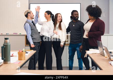 Les jeunes de différentes races et ethnies sont distraits en parlant pendant le travail au bureau, ils rient et parlent entre eux Banque D'Images