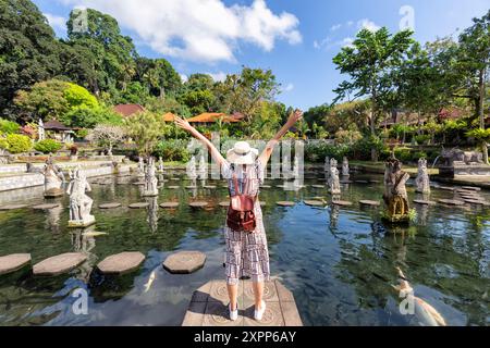 Femme debout dans l'étang avec des poissons colorés à Tirta Gangga Palais d'eau de Bali, Indonésie. Banque D'Images