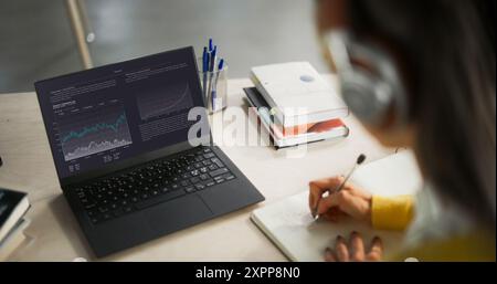 Prise de vue au-dessus de l'épaule avec un étudiant étudiant en commerce et finance dans une bibliothèque. Anonymous Female Learning Online, se préparer pour les examens de gestion Banque D'Images