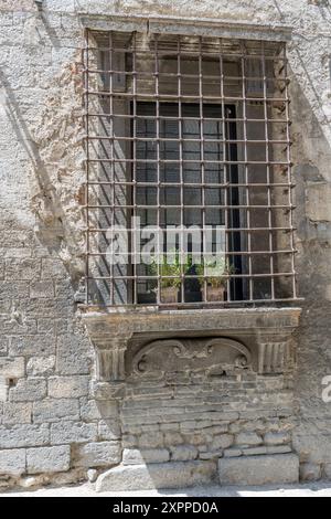 Détail de caillebotis sur la fenêtre de la façade monumentale du bâtiment historique, tourné dans la lumière d'été à Narni, Ombrie, Italie Banque D'Images