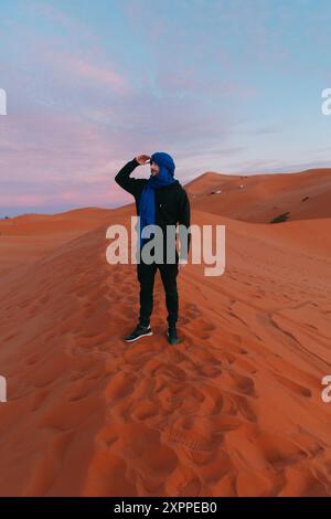 Homme avec une écharpe berbère au sommet d'une dune dans le désert du Sahara Banque D'Images