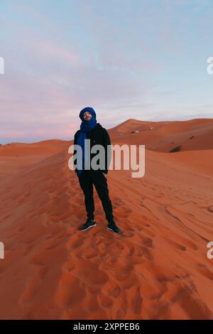 Homme avec une écharpe berbère au sommet d'une dune dans le désert du Sahara Banque D'Images