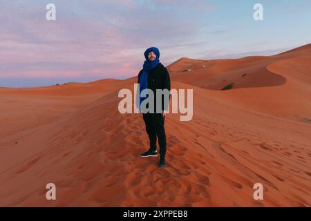 Homme avec une écharpe berbère au sommet d'une dune dans le désert du Sahara Banque D'Images