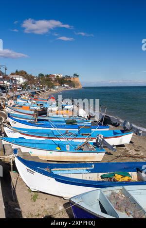 Bateaux de pêche traditionnels alignés le long de la côte de Kitros, Pieria, Grèce, sous un ciel bleu clair et des paysages de bord de mer tranquilles Banque D'Images