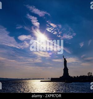 New York, silhouette de la statue de la liberté, Liberty Island, ciel bleu, nuages, soleil, City, État de New York, NYC, États-Unis, Banque D'Images