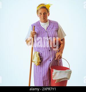 Femme senior sérieuse nettoyante avec équipement de nettoyage Banque D'Images