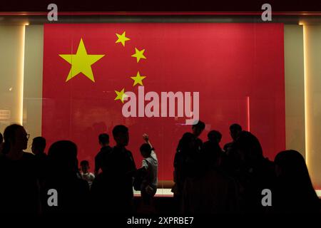 Hong Kong, Chine. 7 août 2024. Les visiteurs prennent des photos devant le drapeau national de la République populaire de Chine à la National Security Exhibition Gallery. La National Security Exhibition Gallery, qui a ouvert ses portes au public mercredi, est la première galerie thématique de la région administrative spéciale de Hong Kong consacrée à la promotion systématique de l’éducation à la sécurité nationale. Banque D'Images