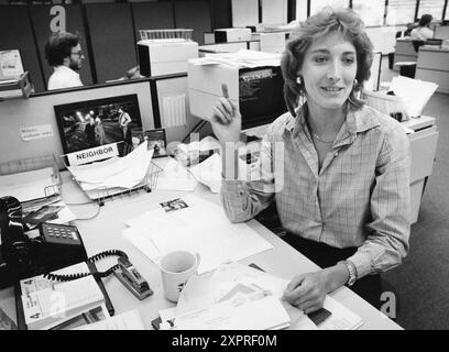 Austin Texas USA, 1984 : rédactrice en chef des sections de nouvelles communautaires dans un grand quotidien au travail avec un terminal informatique, un téléphone à bouton-poussoir noir et des boîtes de réception câblées sur son bureau. ©Bob Daemmrich Banque D'Images