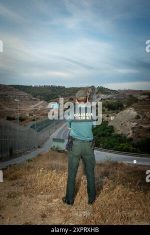 Officier civil de la Guardia observant la clôture de périmètre de la frontière extérieure de l'Union européenne à Melilla, Espagne. Vigilant, l'officier assure la sûreté et la sécurité dans l'enclave espagnole bordant l'Afrique. Banque D'Images