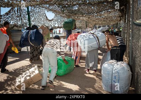 Ressortissants marocains transportant des marchandises à pied à travers la frontière de l'Europe vers l'Afrique à Melilla. Une entreprise de logistique locale supervise ce mouvement de marchandises en juin 2012. Banque D'Images