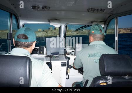 Deux officiers civils de la Guardia surveillent la frontière UE-Afrique depuis un bateau dans l'enclave espagnole de Melilla. Image capturée en juin 2012, montrant les forces de l'ordre en action. Banque D'Images