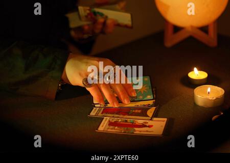 KIEV, UKRAINE - 10 JUILLET 2024 lecteur de tarot cueillant des cartes de tarot. Chandelles dans une pièce sombre. Lecture de tarot et prévision de gros plan sur le lecteur de tarot ou le caissier Banque D'Images