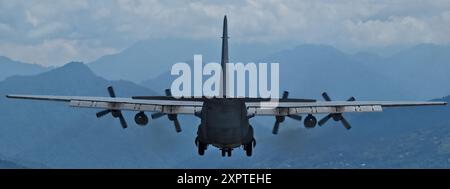 Un avion de transport militaire approche pour atterrir sur fond de montagnes. Banque D'Images