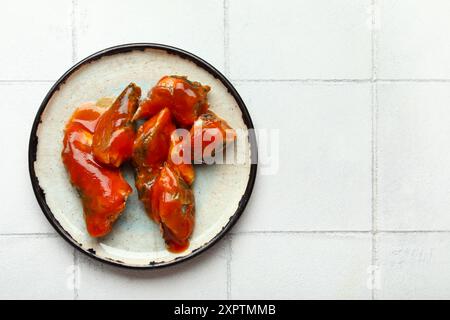 Assiette de poisson en conserve sauce tomate sur table carrelée de blanc Banque D'Images