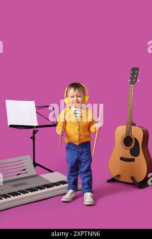 Mignon petit compositeur avec différents instruments de musique sur fond rose Banque D'Images