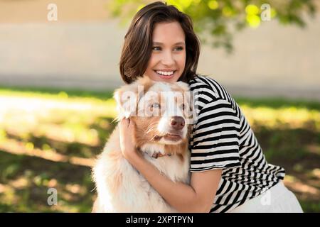 Belle jeune femme avec chien berger australien mignon dans le parc Banque D'Images