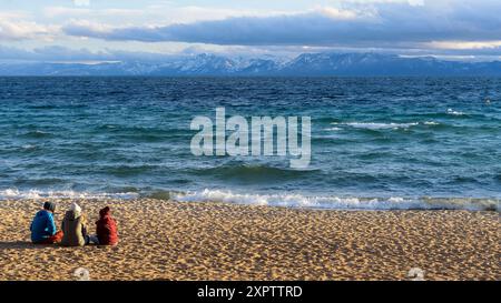 Incline Beach - les jeunes touristes apprécient une soirée de printemps ensoleillée à incline Beach, alors que les nuages de tempête se déplacent sur les sommets de neige dans le lac Tahoe. CA-NV, ÉTATS-UNIS. Banque D'Images