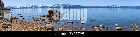 Lac Tahoe - Une vue panoramique sur le lac Tahoe bleu, entouré de sommets enneigés et d'une rive rocheuse, par une journée ensoleillée de printemps. Logan Shoals Vista point. Banque D'Images