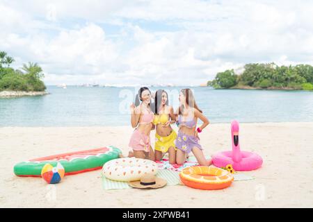 Trois amies asiatiques profitant d'un pique-nique tropical au bord de la plage Banque D'Images