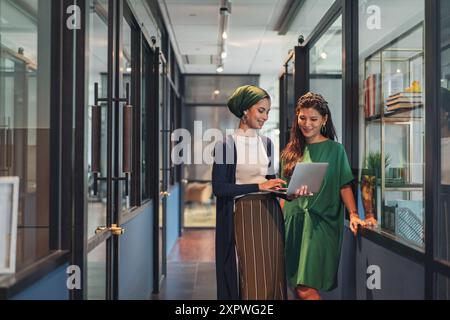 Deux femmes d'affaires asiatiques en tenue décontractée discutant du travail dans le couloir du bureau Banque D'Images