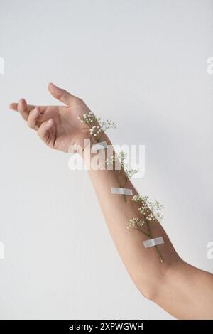 Bras, fleurs et santé mentale avec modèle en studio pour la conscience, la croissance ou la guérison naturelle. Soins de santé, médical et bien-être avec personne sur gris Banque D'Images