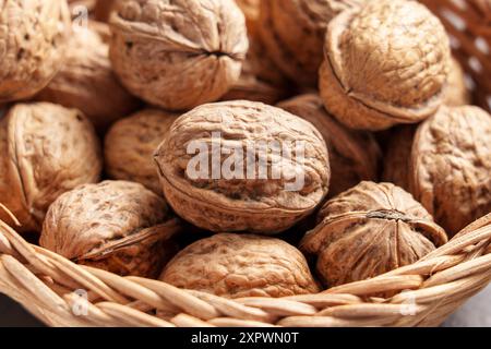 Graines de noix fraîches dans un bol en rotin tressé en bois authentique gros plan. Noix entières non craquelées biologiques en coquille. Banque D'Images