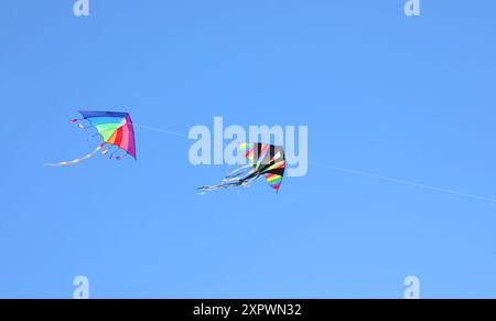 deux grands cerfs-volants colorés avec des couleurs arc-en-ciel volant dans le ciel bleu attaché à une ficelle Banque D'Images