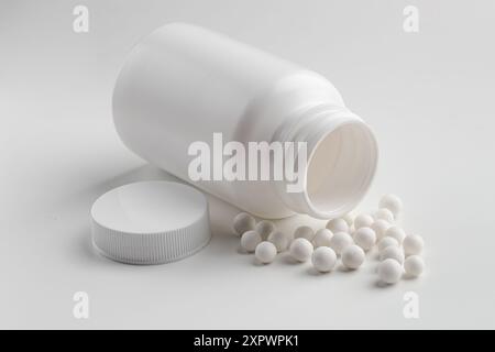 Remède homéopathique. Bouteille avec de nombreuses pilules sur fond blanc Banque D'Images