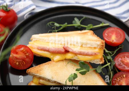 Morceaux de pain grillé avec fromage fondu, jambon et tomates sur la table, gros plan Banque D'Images