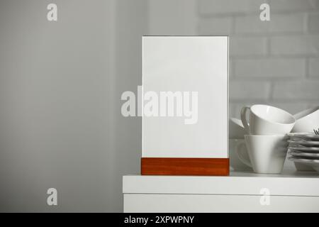 Porte-menu et vaisselle propre sur la table blanche à l'intérieur, espace pour le texte Banque D'Images