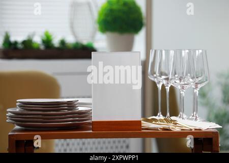 Porte-menu, vaisselle propre et couverts sur la table en bois à l'intérieur Banque D'Images