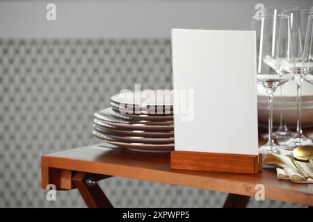 Porte-menu, vaisselle propre et couverts sur la table en bois à l'intérieur Banque D'Images