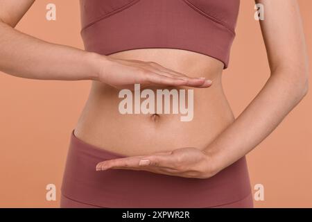 Une digestion saine. Femme tenant quelque chose près de son ventre sur fond beige, gros plan Banque D'Images