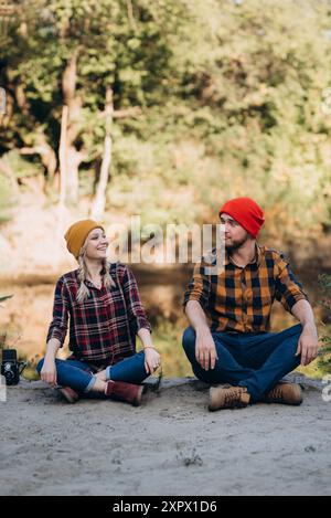 Un homme chauve avec une barbe et une fille blonde dedans des chapeaux brillants sur le fond de la rivière sont pris photos avec un ancien appareil photo Banque D'Images