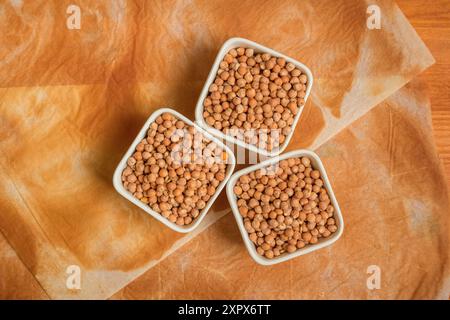 Trois bols de pois chiches avec du papier cuisson brûlé sur la table, vue de dessus Banque D'Images