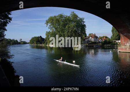 Un rameur tôt le matin longe la Tamise, vers le pont ferroviaire Maidenhead, conçu par Isambard Kingdom Brunel. Date de la photo : jeudi 8 août 2024. Banque D'Images