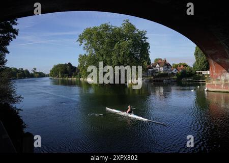 Un rameur tôt le matin longe la Tamise, vers le pont ferroviaire Maidenhead, conçu par Isambard Kingdom Brunel. Date de la photo : jeudi 8 août 2024. Banque D'Images