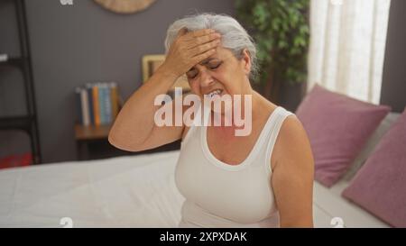 Femme éprouvant, mal de tête, cheveux gris, assis, lit, chambre, maison, intérieur, tenue, tête Banque D'Images