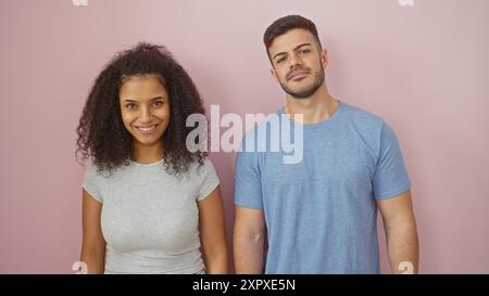 Une femme et un homme souriants se tiennent ensemble contre un mur rose, rayonnant une ambiance de relation détendue et heureuse. Banque D'Images