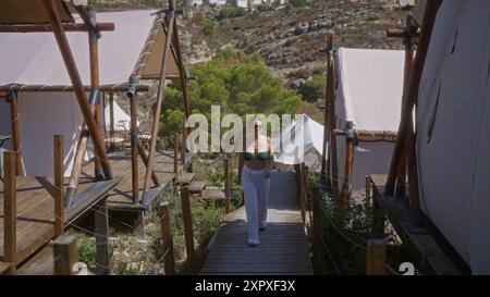 Une belle jeune femme hispanique aime camper en plein air dans une tente en afrique, mettant en valeur un site de glamping serein entouré par la nature. Banque D'Images