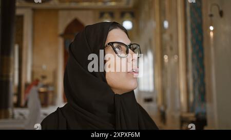 Une femme réfléchie portant un hijab contemple l'architecture islamique dans le village culturel katara, doha, qatar. Banque D'Images