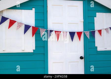 Bright Bunting sur un colorée, pittoresque, Turquoise et White Beach Hut sur le front de mer ouest de Ho surplombant la plage et l'estuaire de Torridge. Banque D'Images