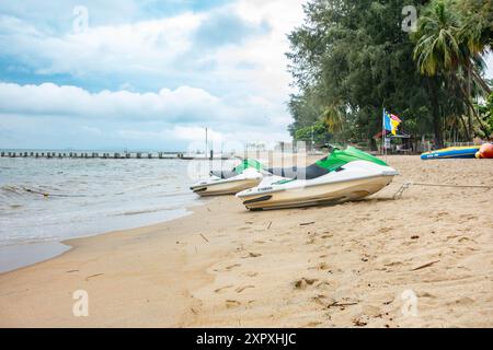 Une vue le long de la plage de Batu Ferringhi à Peragn, Malaisie. Quelques jet skis sont garés sur le sable doré. Banque D'Images